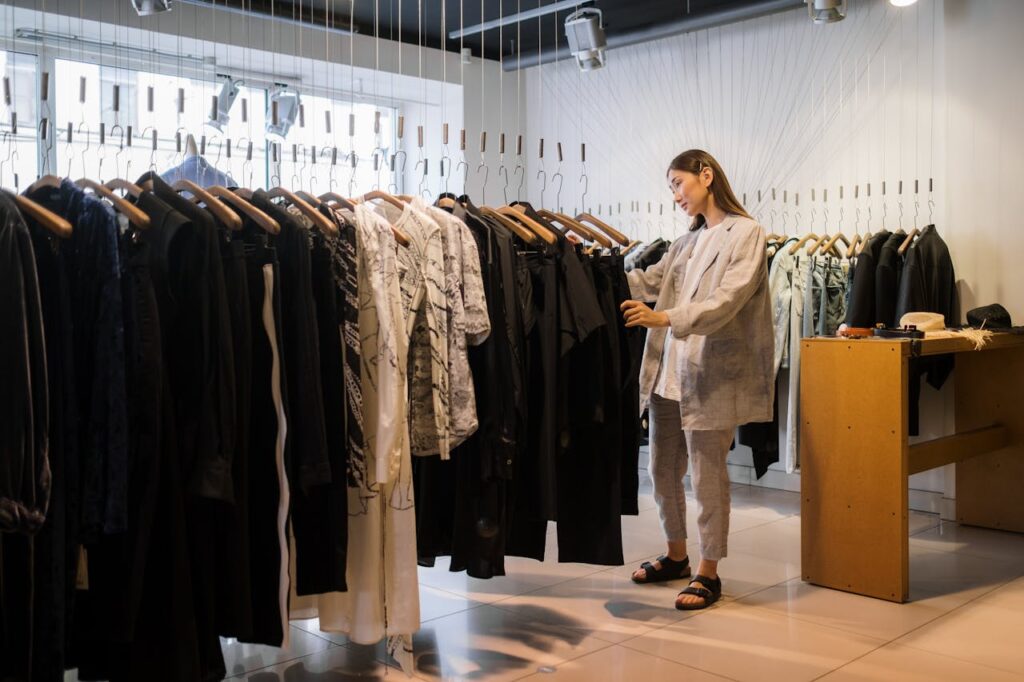 Stylish woman browsing through racks of modern clothing in a trendy boutique.