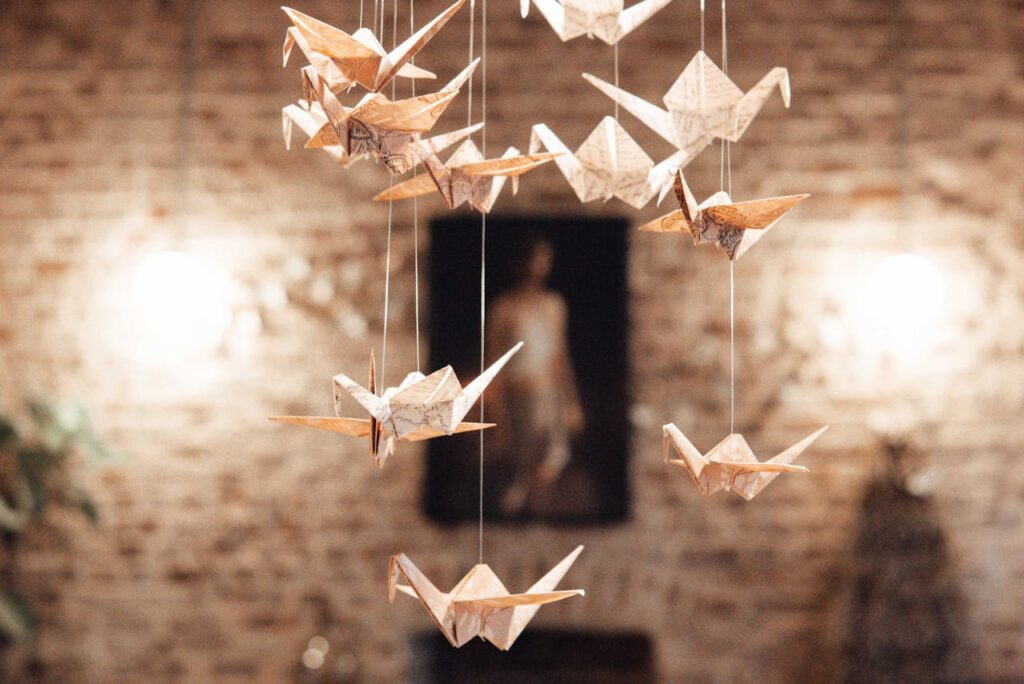 anging paper origami cranes in a cozy, warmly lit interior space, representing traditional Japanese craftsmanship.