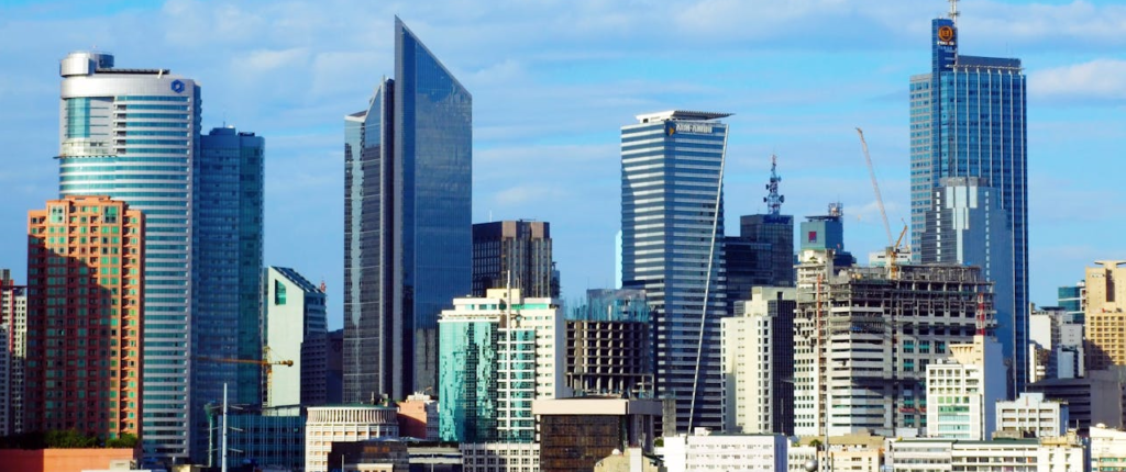 A panoramic view of the Manila skyline, showcasing modern skyscrapers, commercial buildings, and ongoing construction.